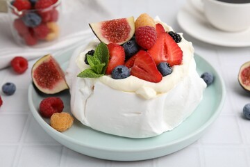 Pavlova cake (meringue dessert) with whipped cream, fresh berries, mint and fig on white table, closeup