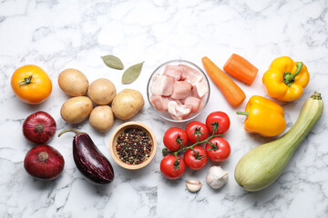 Uncooked ingredients for stew on white marble table, flat lay