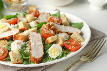 Tasty Caesar salad with chicken and tomatoes on white wooden table, closeup