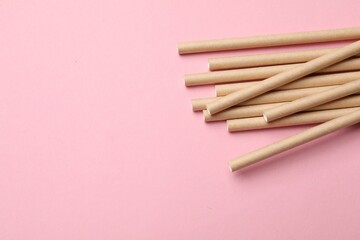 Bamboo drinking straws on pink background, top view. Space for text