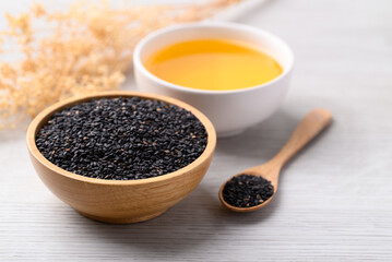 Black sesame seeds and oil (Cold pressed) in bowl on white table, Food ingredient
