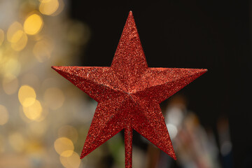 una estrella decorativa de color rojo con fondo desenfocado de &aacute;rbol de navidad