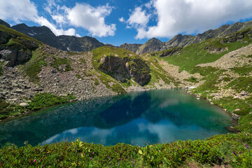 View of the Dukka lake "Rybka" on the Malaya Dukka River on the slopes of the Arkasar ridge in the North Caucasus on a sunny summer day, Arkhyz, Karachay-Cherkessia, Russia © Ula Ulachka