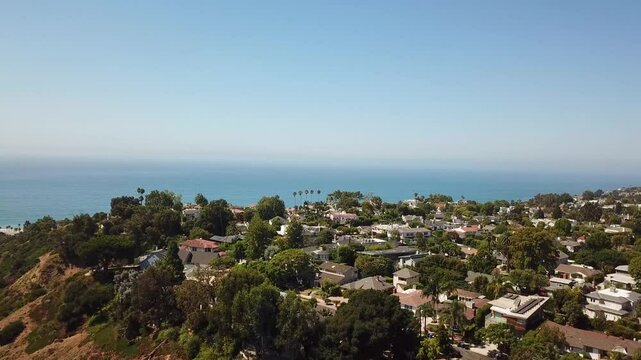 Upscale Neighborhood of Pacific Palisades in Los Angeles with picturesque Pacific Ocean view in summer. Mansions and Villas located on mountain along coast of California. Aerial establishing wide shot