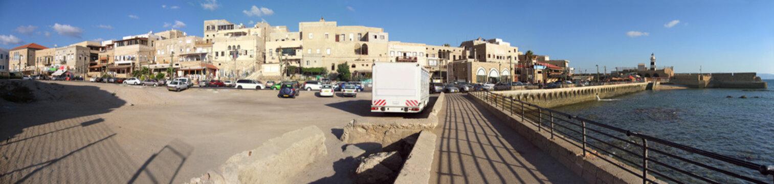 Ancient stone embankment with fortress and Akko historical cityscape with lighthouse panoramic view