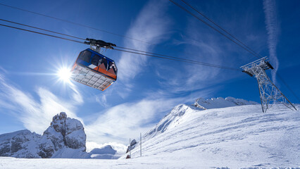 A breathtaking panoramic view of snow-covered mountain peaks and a ski cabin under a bright blue...