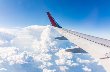 Fototapeta premium View from the airplane window at a beautiful cloudy sky and the airplane wing