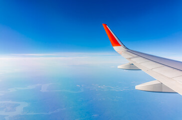 Obraz premium Aerial view from airplane window above green ground. View from the airplane window with beautiful clouds at sunrise
