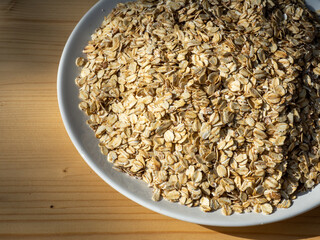 Dry oatmeal in a plate on the table. Simple and healthy breakfast. Raw oatmeal flakes heap. Porridge with fiber