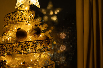 árbol de navidad con reflejo en la ventana de noche lluviosa y bokeh dorado