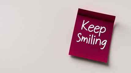 Sticky Note: A single maroon sticky note with the words "Keep Smiling" written in simple, clear handwriting. The sticky note is placed on a plain white background, promoting positivity and joy.


