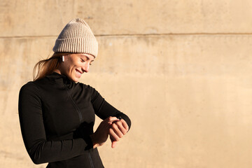 Female runner checking smart watch. Happy woman using smart watch to play music for exercising...