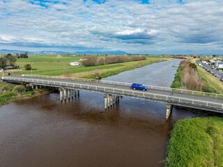 Fototapeta premium Bridge crossing the Waihao River and farmland in Ngatea, Waikato, New Zealand.