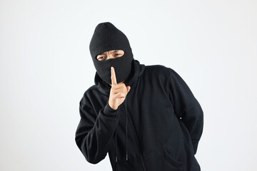 Thief in Black Balaclava Holding Fingers on Lips, Making Hush Sign