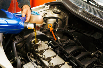 A man is pouring oil into a car engine. Concept of maintenance and care for the vehicle