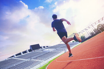 Fototapeta premium Fit young man running sprinting at the racetrack. Fit runner fitness runner during outdoor workout at racetrack.