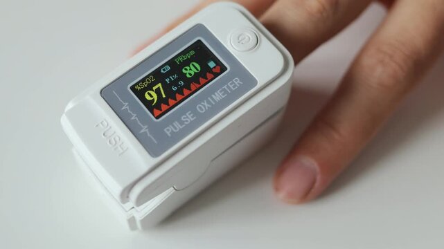 Unrecognizable woman monitoring blood oxygen level using digital fingertip oximeter to measure her pulse and saturation ensuring proper health care during routine medical checkup