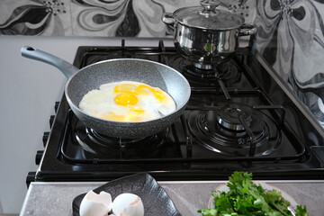 A non-stick frying pan cooks an omelet on a gas stove.