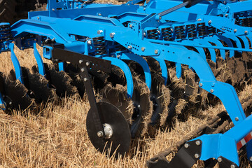 Close-up of a large modern plow blue color or disc harrow for cultivating the land. New model of...