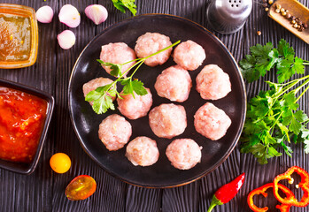 Fresh raw beef meatballs with spices and tomato sauce