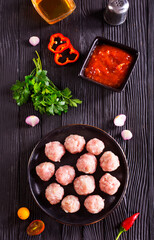 Fresh raw beef meatballs with spices and tomato sauce