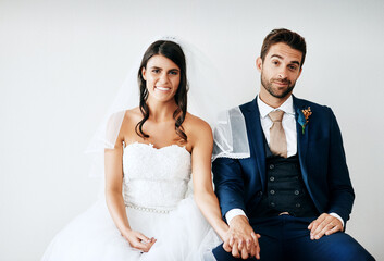 Bride, groom and holding hands portrait in studio for marriage with smile, wedding and trust...