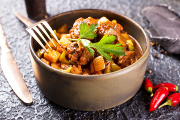 stew in tomato sauce with vegetables in gray bowl