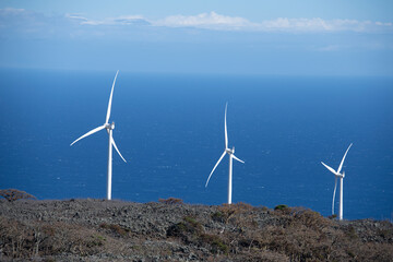 Three white windmill turbines in Hawaii framed by the Pacific Ocean
