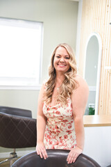 Smiling woman in a floral dress, standing in a bright, modern sa