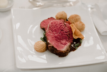 Perfectly cooked roast beef, pommes duchesse in a fine dining setup.