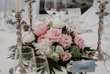 Elegant wedding centerpiece with pink roses and silver candle holders.