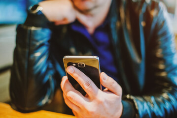 A man writes in her smartphone while sitting in a cafe
