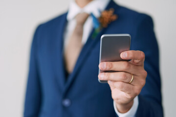 Hand, groom and smartphone in studio for marriage with smile, wedding schedule and relationship trust. Social media, status update and commitment for man, excited and partnership on white background