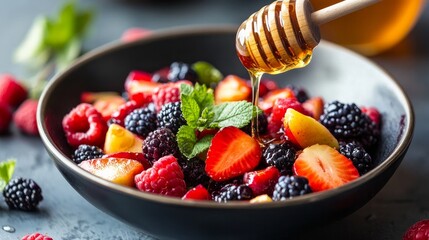 adding honey to a fruit salad with berries
