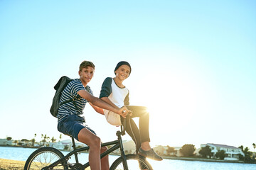 Outdoor, portrait and boys with bicycle for riding, paddle and coordination with balance for brothers. Lagoon, children and siblings with bike for transport, travel and bonding together in nature