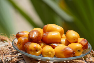 Close up of Ramadan food sweet fruit dates in a plate green background