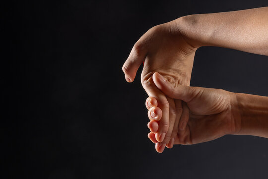 close up of female hands doing hand stretching on dark background, hand warm up concept