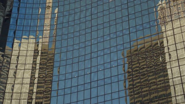 Buildings reflecting on skyscraper windows. Big city architecture with urban background. Reflective glass windows on high-riser in downtown. Sun flare. Tall structure with offices and apartments