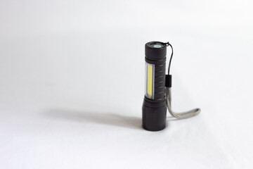 Modern black metal LED flashlight. Portable flashlight with white background.