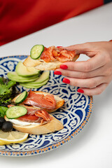 Woman enjoying a snack of smoked salmon and cucumber on toast with a fresh salad