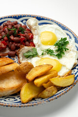 Delicious breakfast plate featuring eggs, beans, bacon, and potato wedges served on a decorative dish