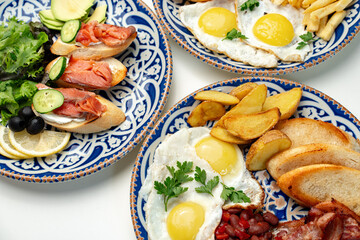 Traditional breakfast plates featuring eggs, sausages, and various accompaniments arranged...