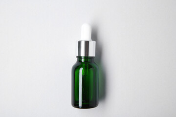 Essential oils in bottle on light background, top view