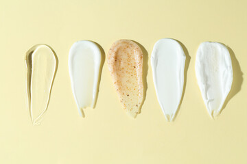 Smears of different cosmetic products on beige background, flat lay