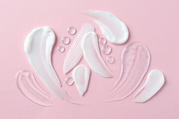 Smears of different cosmetic products on pink background, flat lay