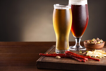 Glasses with different types of beer and snacks on wooden table, closeup. Space for text
