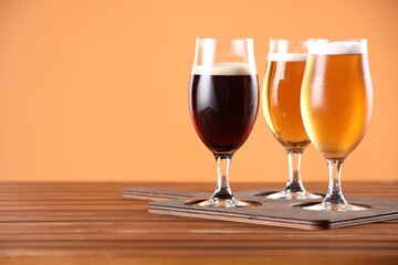 Glasses with different types of beer on wooden table. Space for text