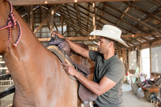 Man putting saddle on horse