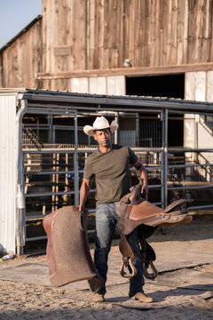 Man holding a heavy saddle looking at camera