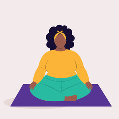 Front View Of One Overweight Black Woman In Sports Clothing Meditating While Sitting On A Mat With Her Legs Crossed.